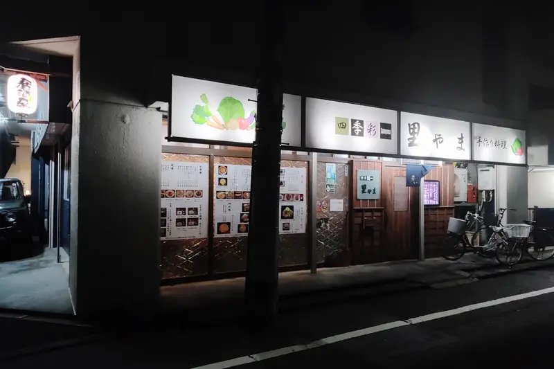 四季彩 里やま_窓にメニューが貼られていて、白い目立つ看板と木目調の外壁の外観